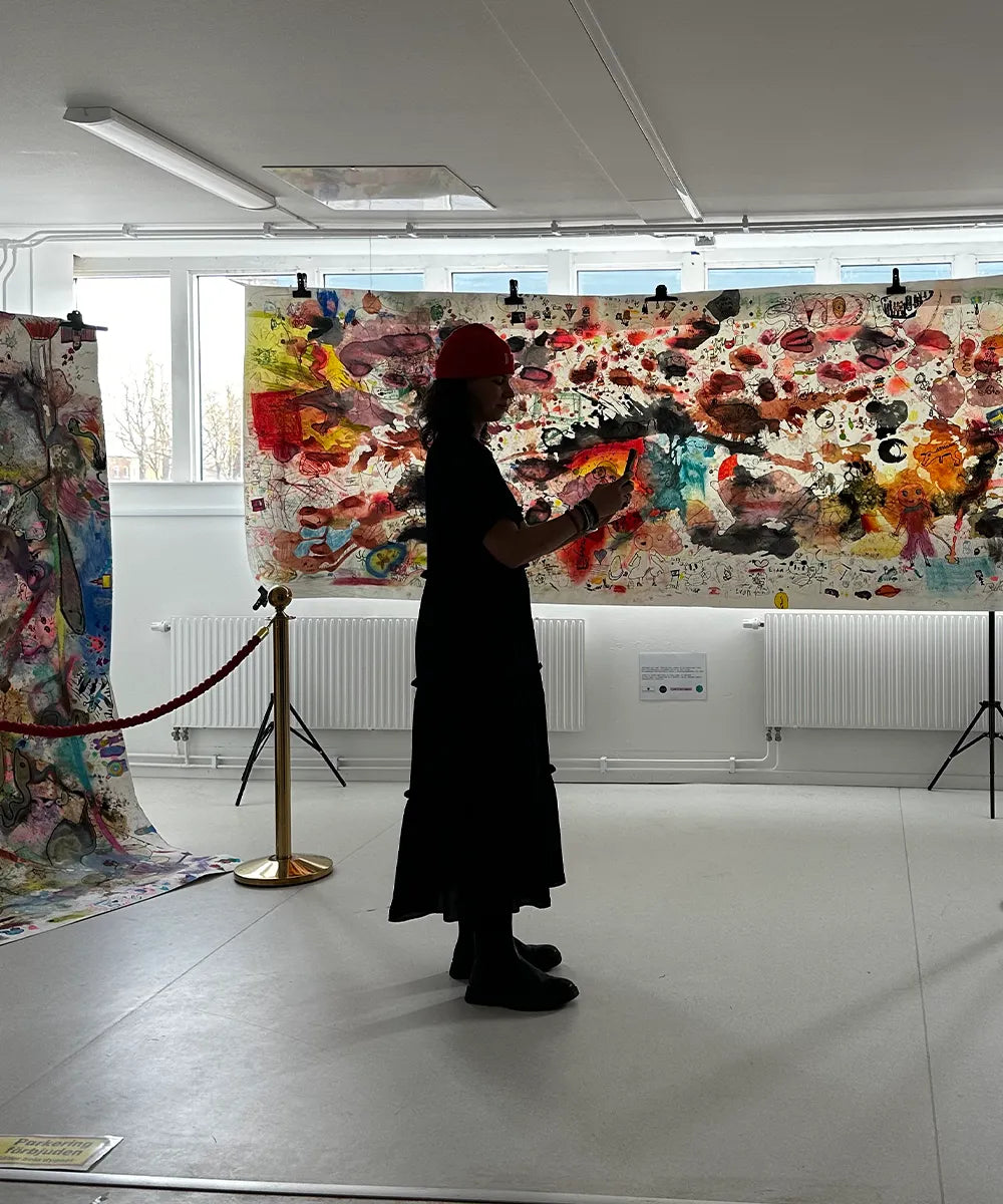 en siluett av en person som står framför flera stora färgglada konstverk