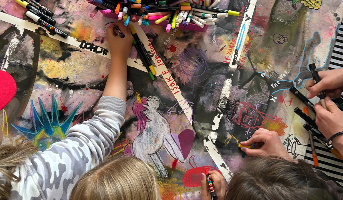 barn som samskapande målar på en stor canva med färgglada kritor och pennor