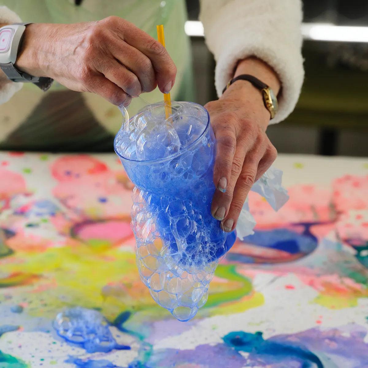 färgglatt vatten i en blå ton bubblar och har runnit över koppens kant
