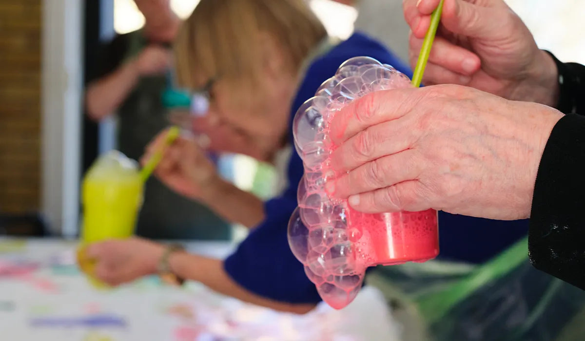 färgat vatten i en plastkopp som någon håller, det bubblar ut färg.