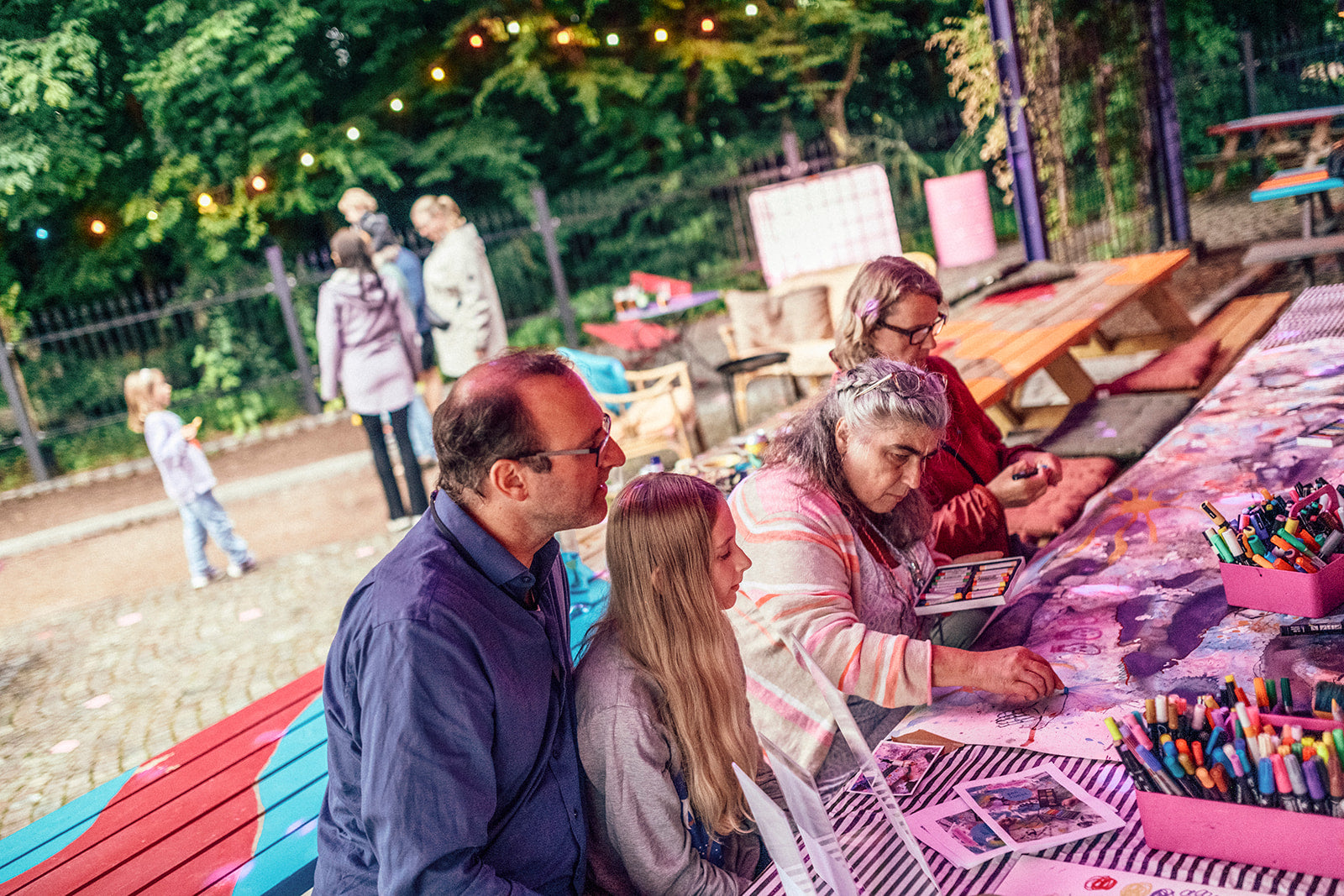 en mix av åldrar på personer som tillsammans skapar ett stort konstverk i en park